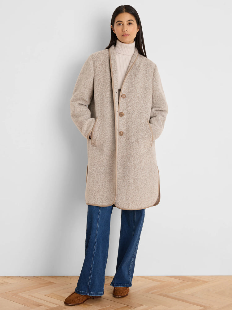 Light beige jacquard top coat. Collarless, mid-thigh length, with tan piping detail and three brown buttons.