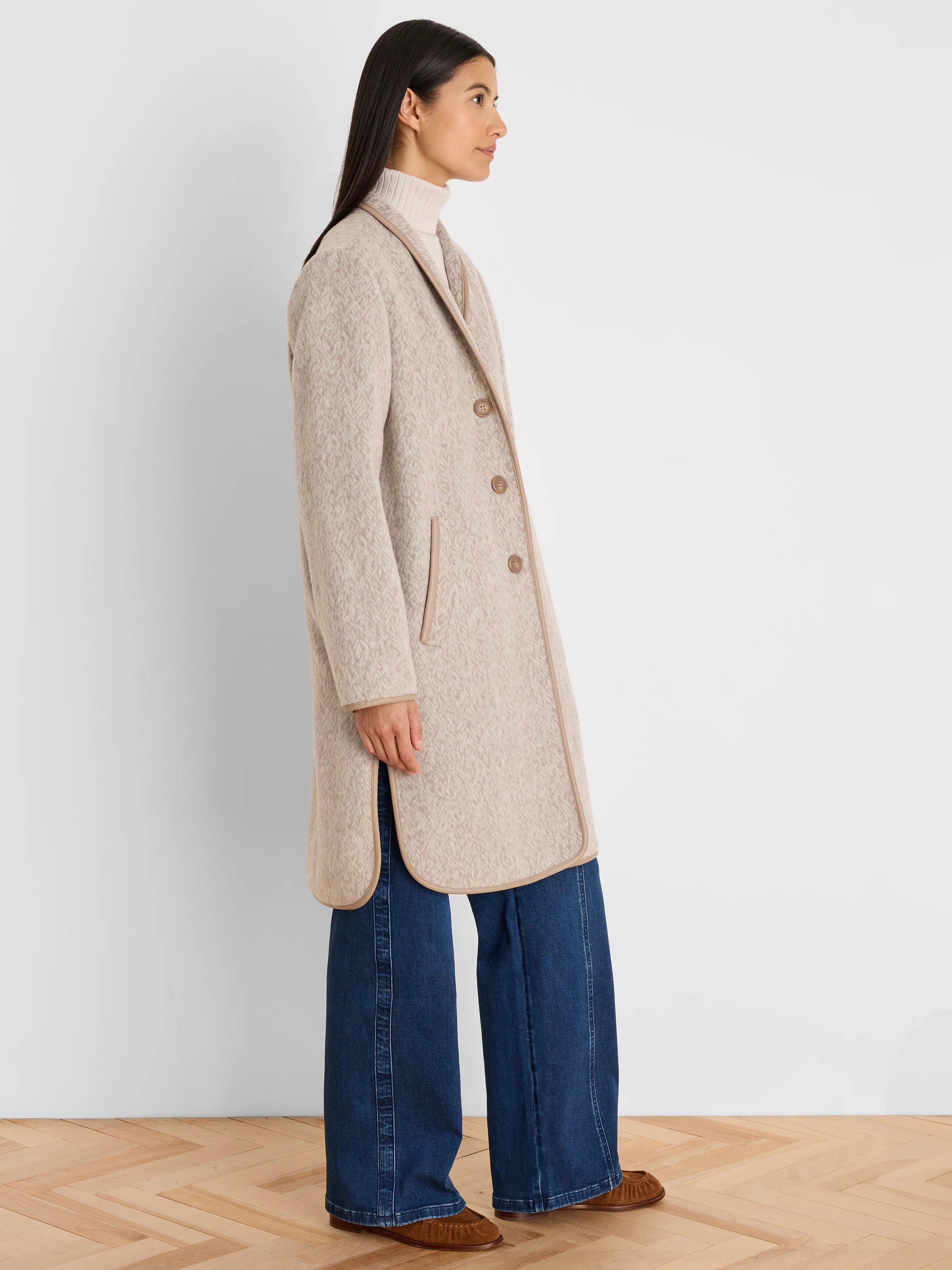 Light beige jacquard top coat with brown trim, button front, notched lapel, and rounded hem with side slits.