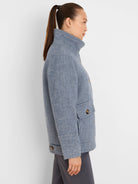 Light blue tweed coat, hip-length, with a high collar, two front flap pockets, and dark brown buttons.