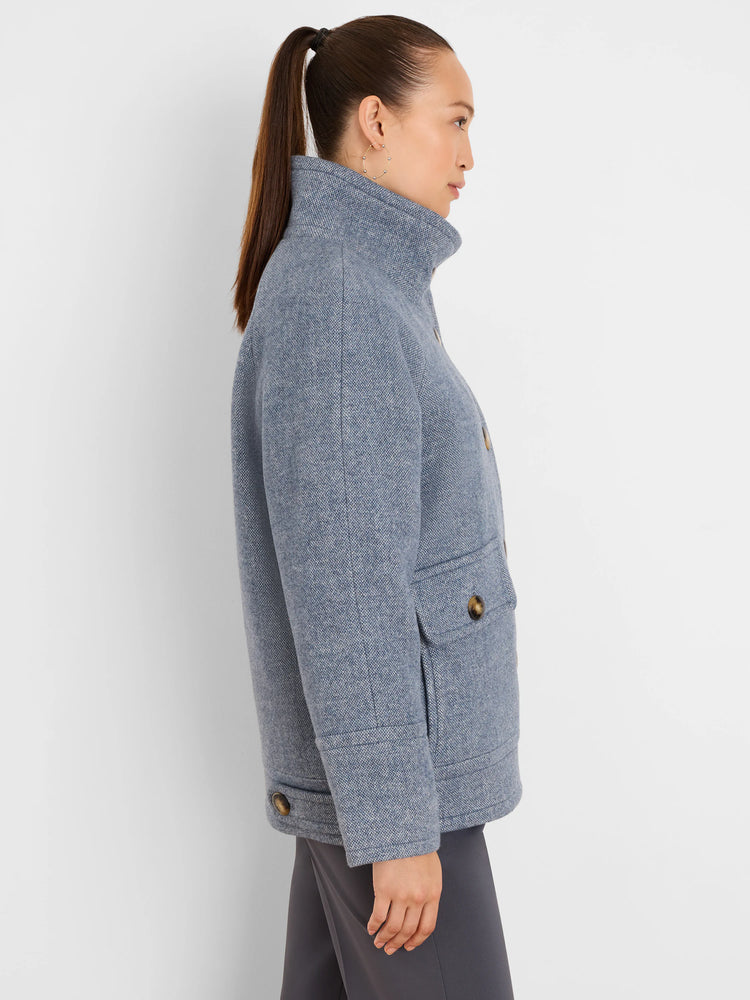 Light blue tweed coat, hip-length, with a high collar, two front flap pockets, and dark brown buttons.