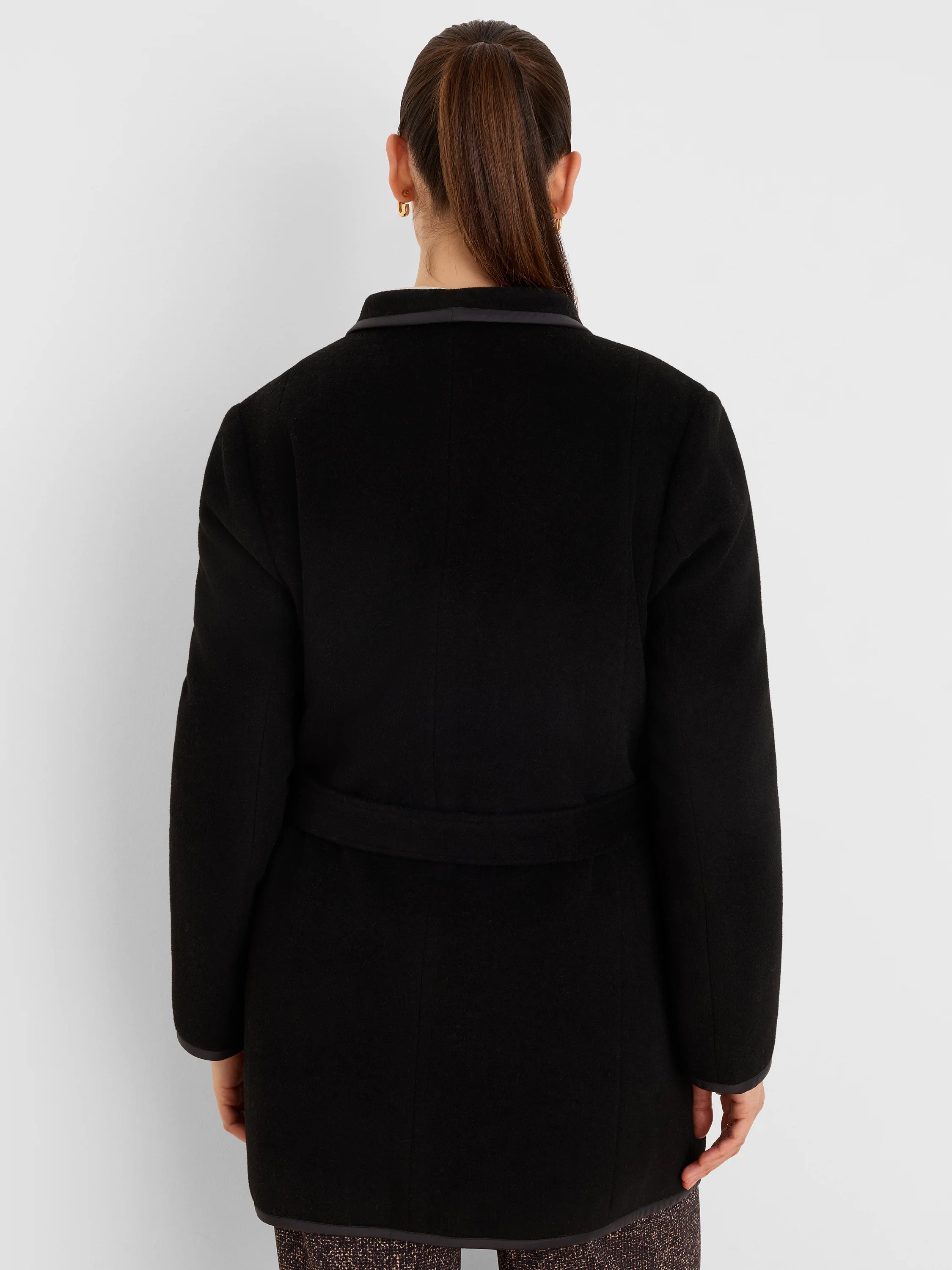 Black quilted top coat from back, with dark trim revealing a patterned, textured reverse side.