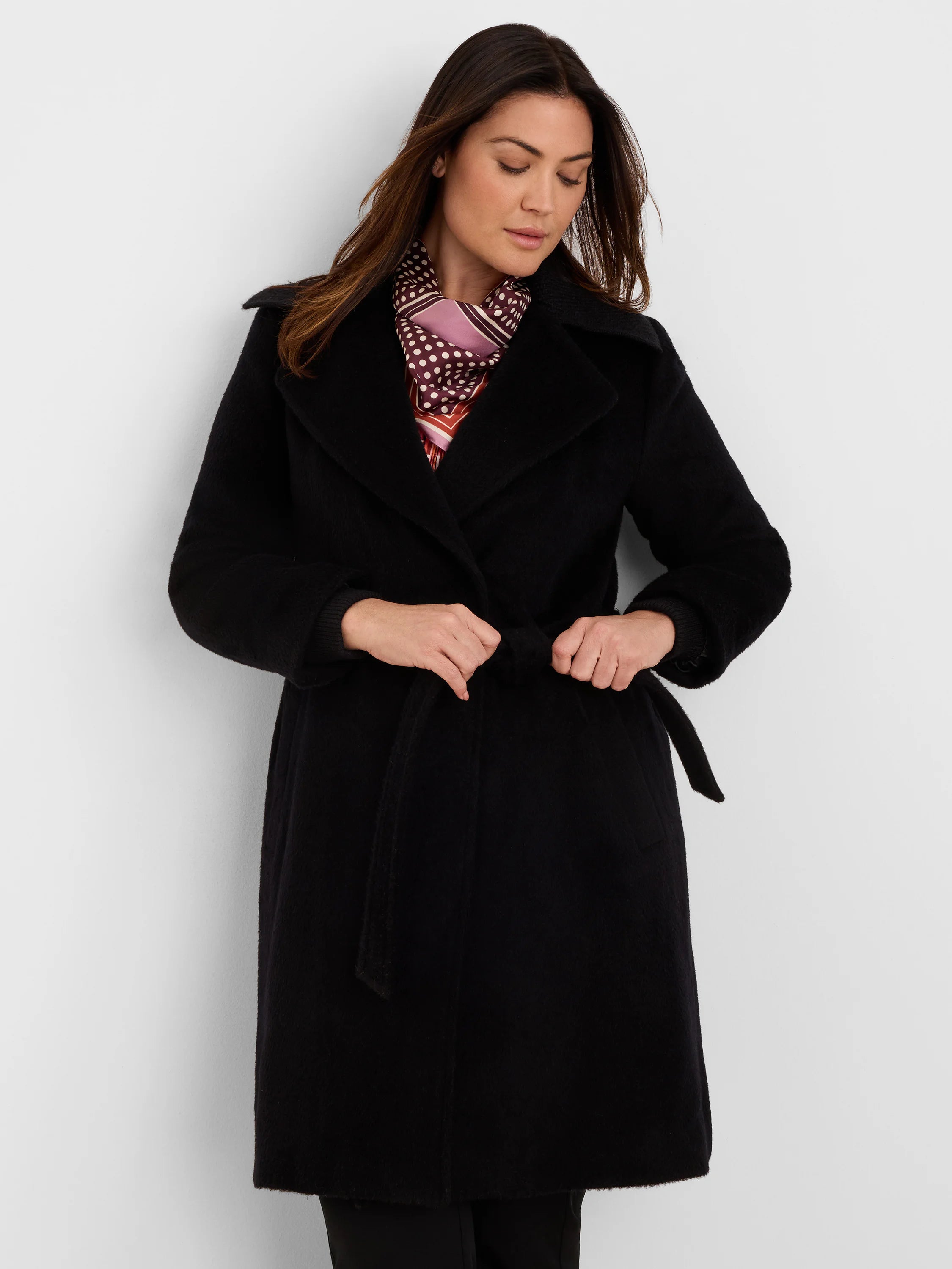 Black wrap coat with wide lapels and belted waist. Soft, textured fabric.