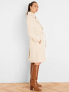 Knee-length cream wrap coat with tie belt, soft texture.