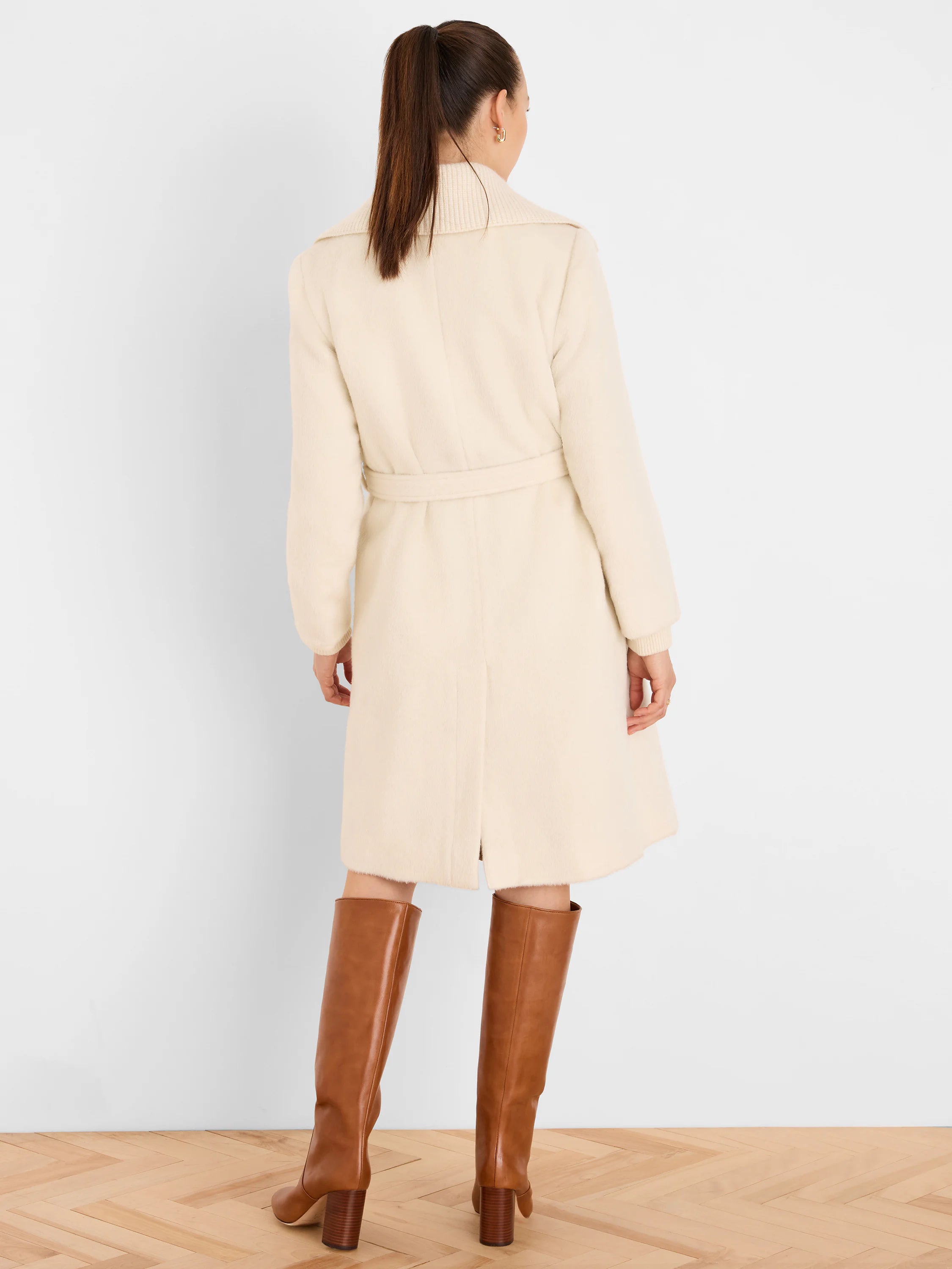 Cream knee-length wrap coat with a wide ribbed collar, tie-waist, and back slit. Soft texture.