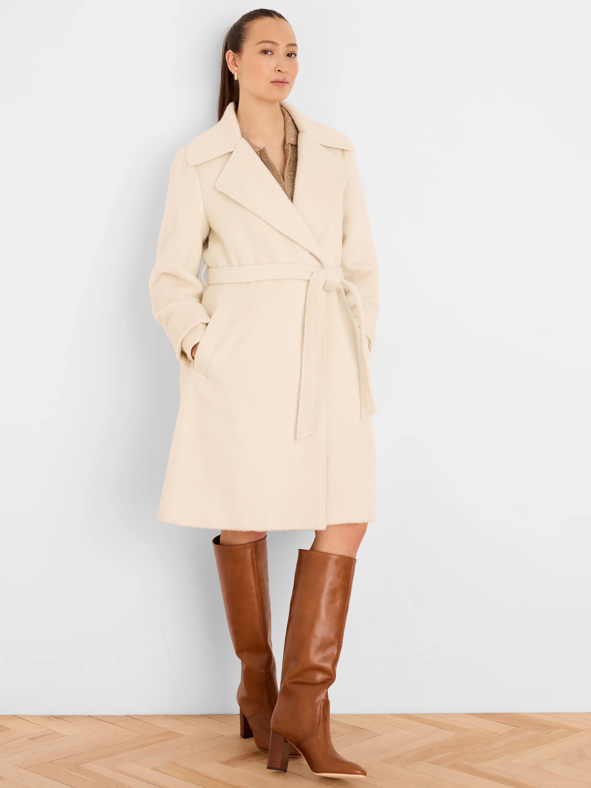 Cream wrap coat with wide lapels, tie belt, soft texture, and functional pockets. Reaches above the knee.