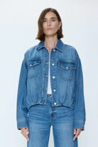 Medium blue denim jacket with cinched blouson hem, collar, silver buttons, and flap chest pockets.