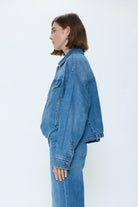 Medium blue denim blouson jacket. Features oversized fit, classic collar, flap chest pockets, and contrast stitching.
