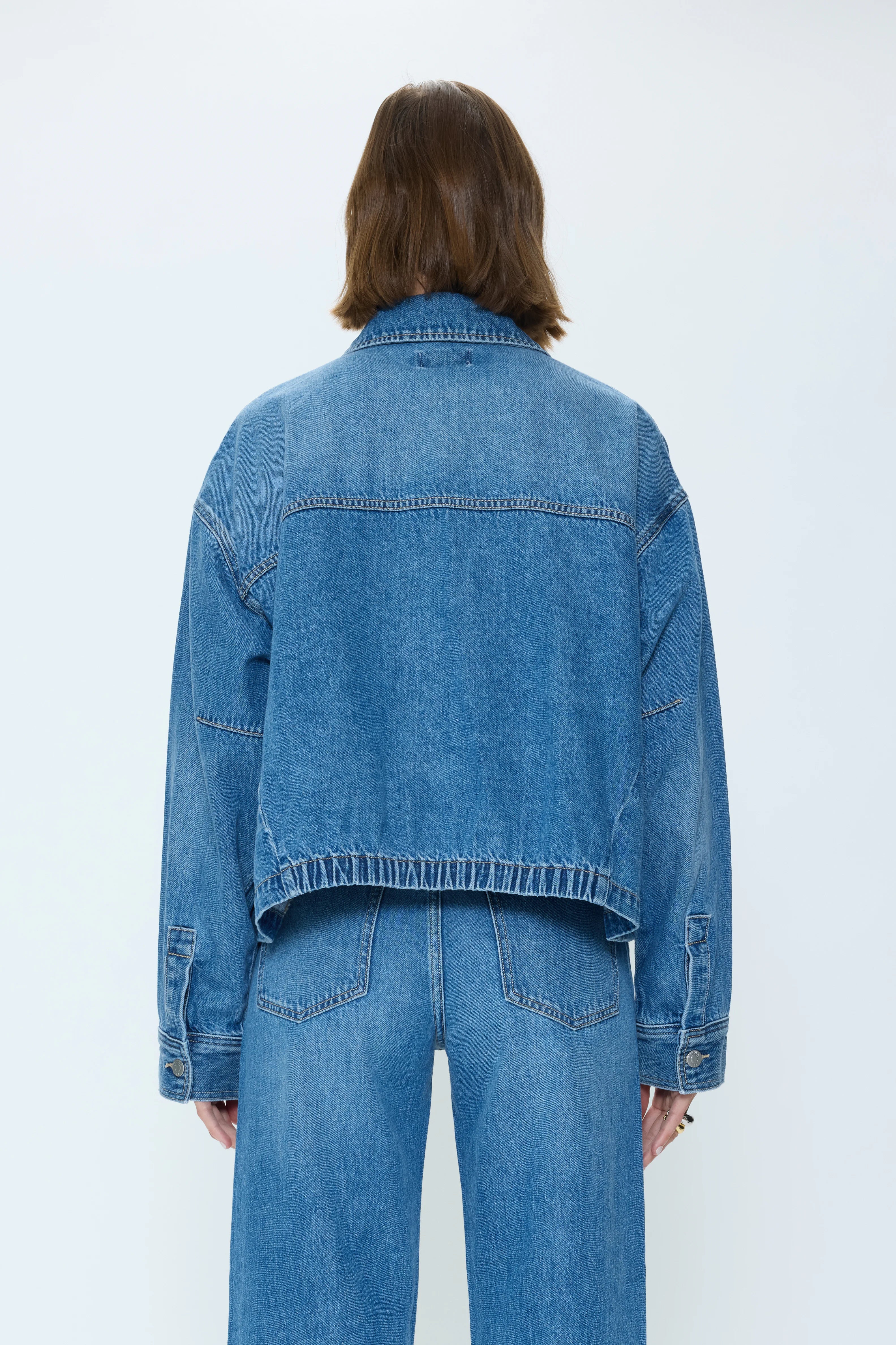 Medium blue denim jacket, back view, with a relaxed fit and an elasticated bottom hem.