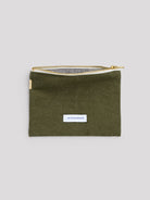 Olive green pouch with gold zipper, white brand label on front, and black & white checkered lining visible.