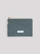 Dark teal woven cotton pouch with gold zipper and white tape, and a white 'LES PENSIONNAIRES' label.