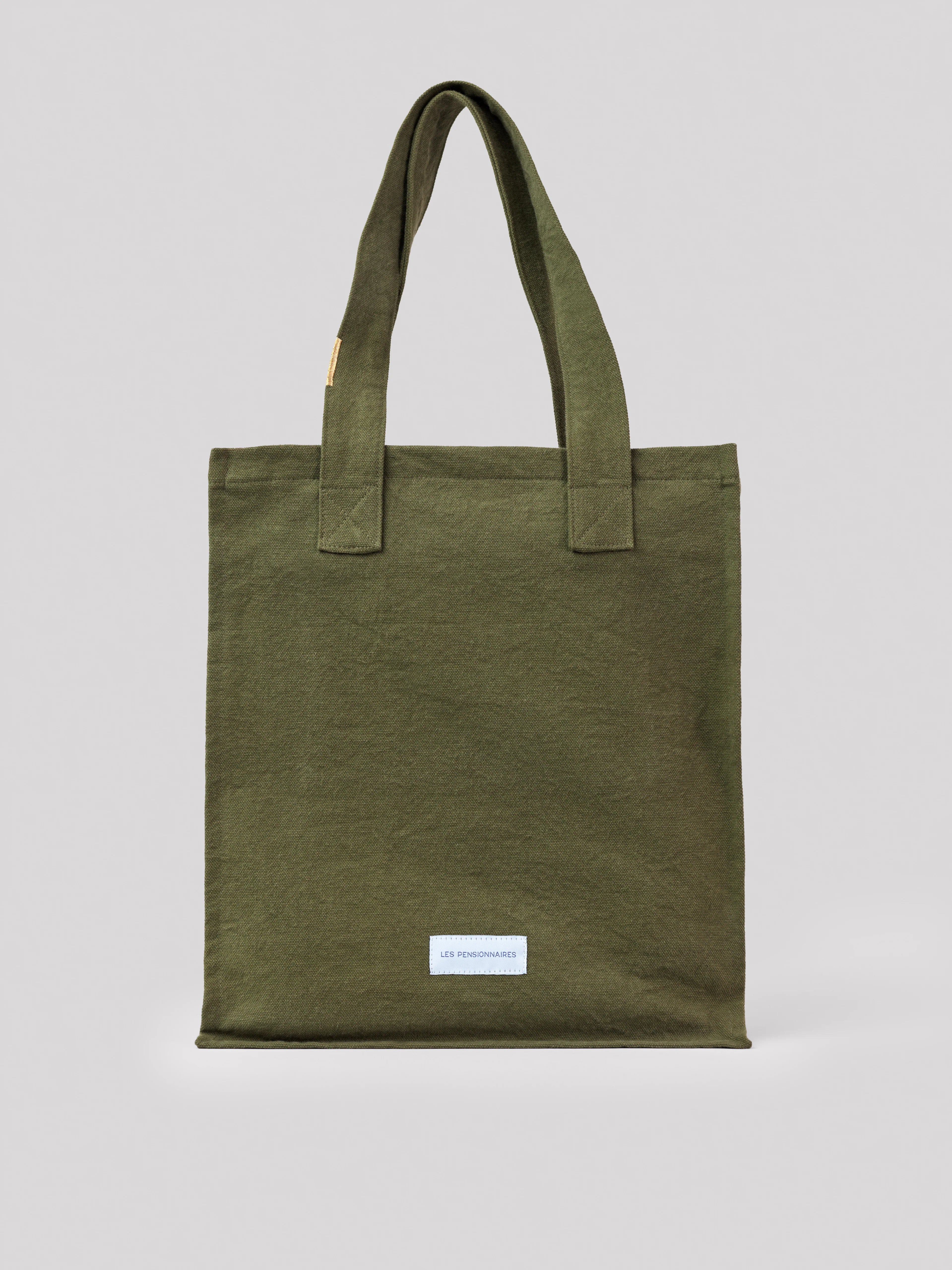 Olive green cotton tote bag with two fabric handles. Small white 'LES PENSIONNAIRES' label on the front.
