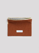 Rust orange cotton zipper pouch with a gold zipper, white trim, and visible black/white checkered lining. Small white...
