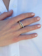 Mixed metal trinity ring with smooth silver, gold pavé, and dark textured bands on a hand.