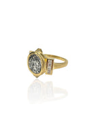 Gold ring with a textured gray coin center and a rectangular accent featuring several clear stones.