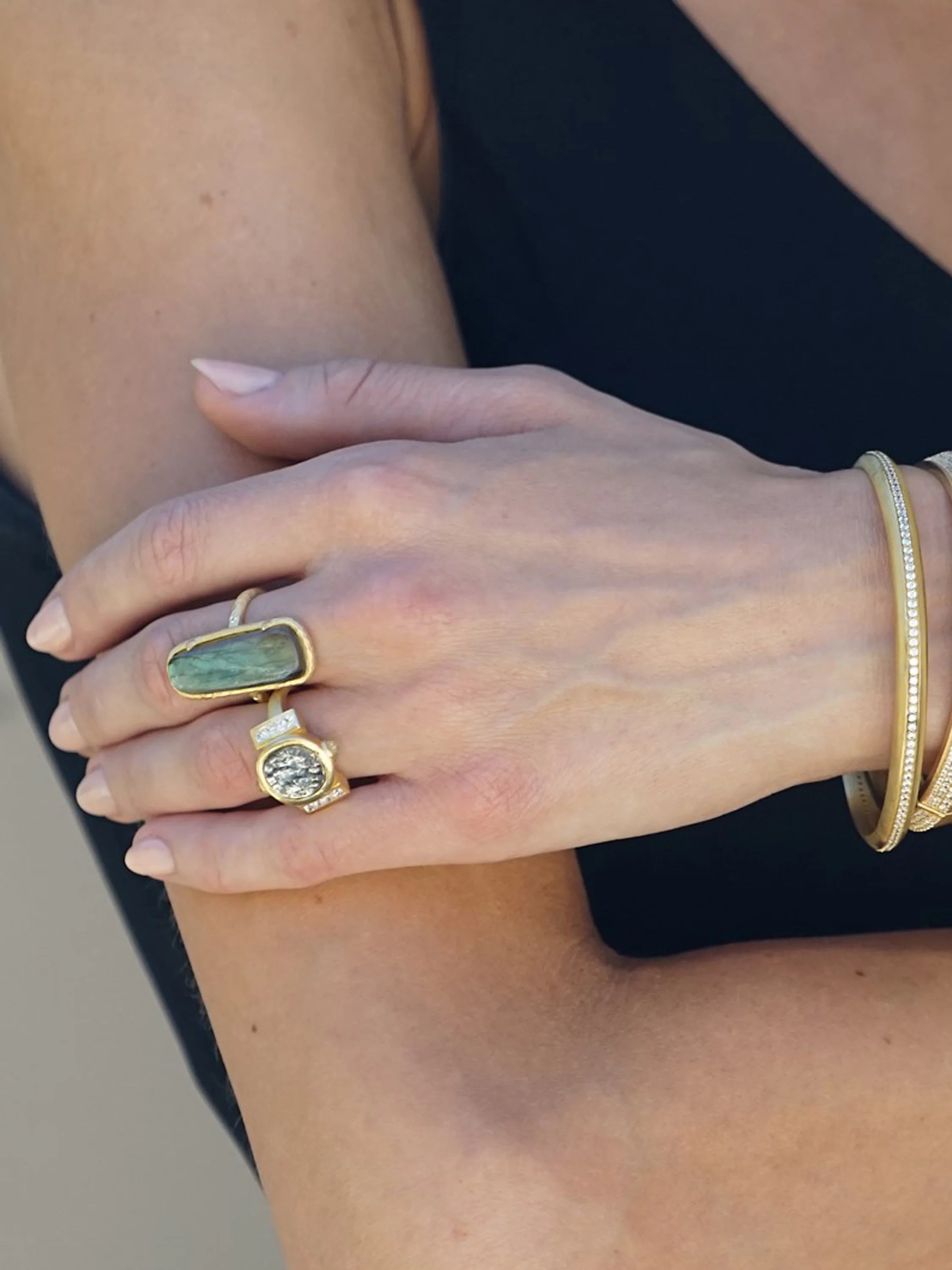 Gold ring with a round, aged silver-toned coin center, flanked by tiny clear gems.