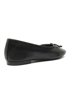 Smooth black ballet flat with a soft square toe, small bow detail, and a low heel. Side view.