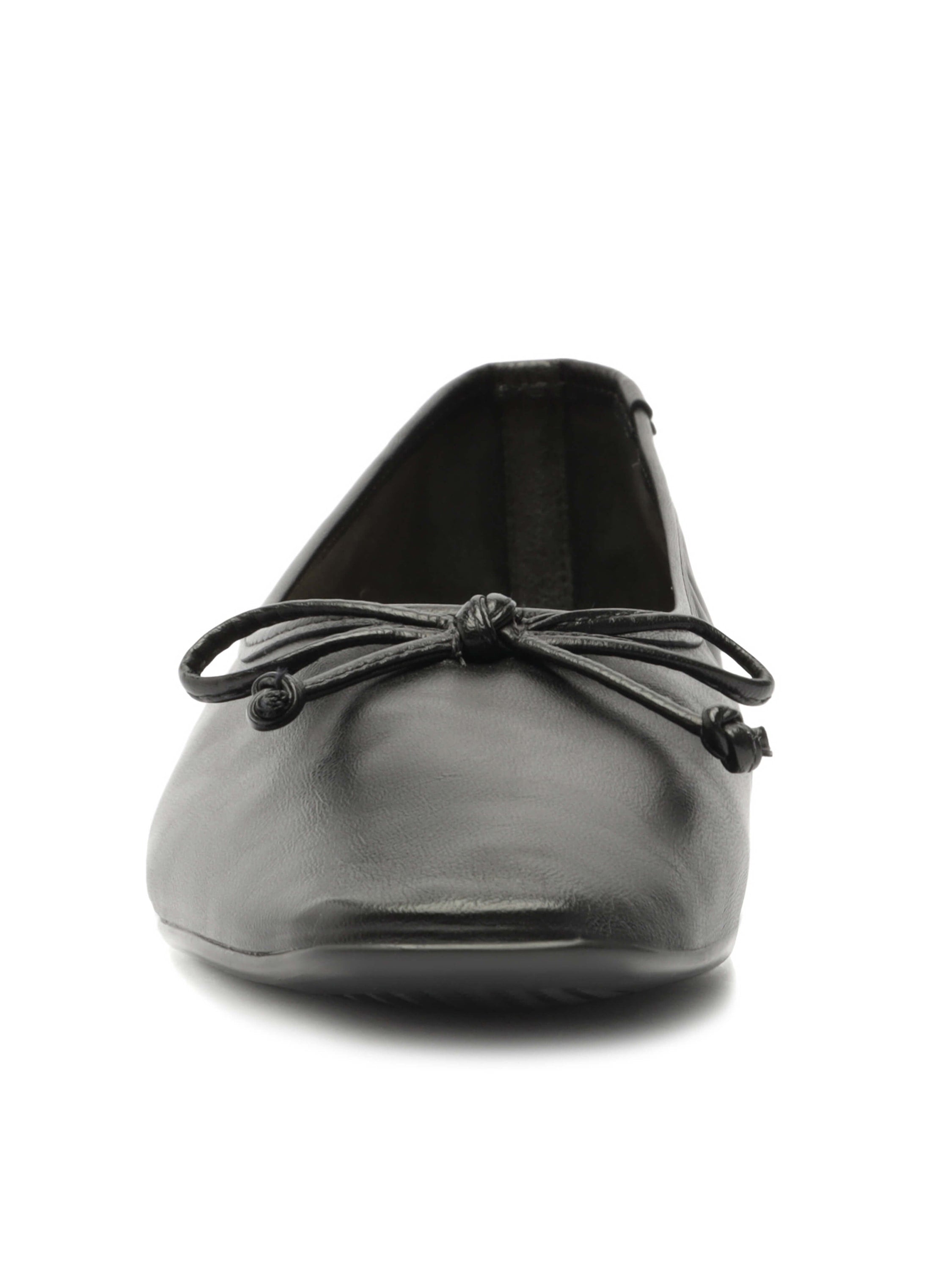 Black leather slip-on flats have a slightly square toe and a matching knotted bow detail.