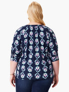 Dark navy top with teal, pink, and beige batik pattern. Three-quarter sleeves.  Back view.