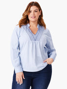Light blue long-sleeve top with dark blue embroidered details at the V-neck.  Long sleeves have slight puff at cuffs.