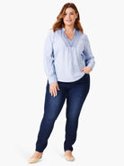 Light blue long-sleeve top with darker blue embroidery at neckline.  Model wears dark wash jeans.