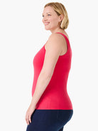 Fitted coral-red tank top with wide straps, worn by a woman with dark jeans.