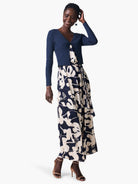 Navy blue cropped cardigan, shown on a model.  The cardigan is ribbed. The model wears a navy and beige floral dress.