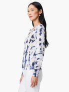 White cardigan with blue, beige, and green abstract print.  Long sleeves, V-neck.