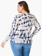 Cream-colored sweater with a blue and dark-navy abstract print.  Long sleeves.  Rear view.