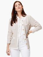 Beige knit jacket with white trim, gold buttons, and patch pockets.