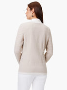 Beige knit jacket, open front, long sleeves, textured fabric.  White underlay visible at collar and hem.