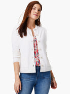 Off-white cardigan, button front, long sleeves. Model wears it over a patterned top and jeans.