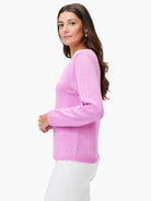Light pink long-sleeve sweater with a rounded neckline, ribbed cuffs & hem, worn by a woman with white pants.