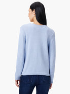 Light blue fine knit sweater on a model, back view. Features ribbed cuffs and hem.