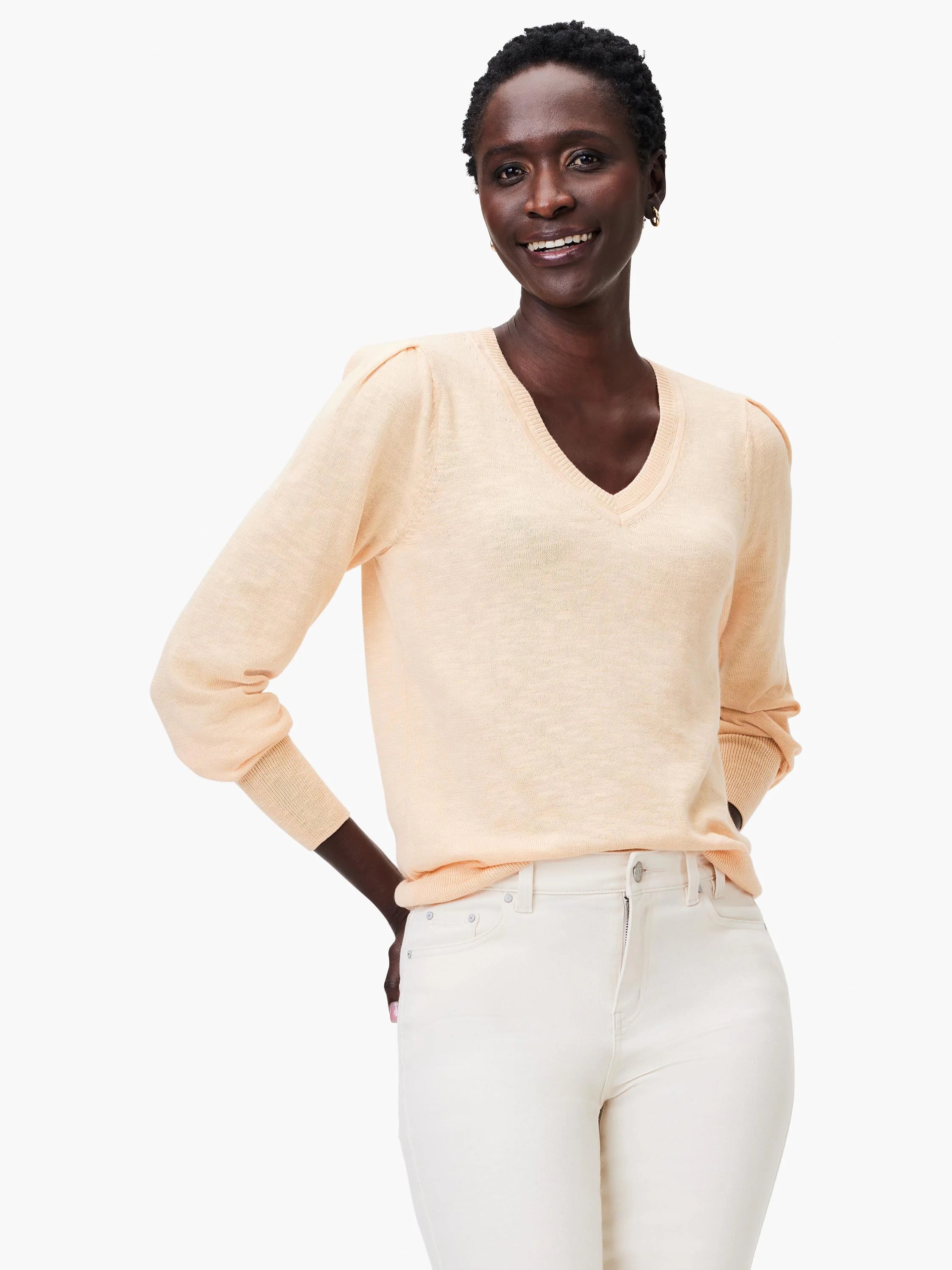 Peach-colored slub knit V-neck sweater with long sleeves and slightly puffed shoulders.