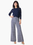 Navy blue pointelle sweater with a geometric pattern.  Model also wears wide-leg pants with a vertical navy and off-white...