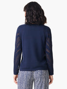 Navy blue pointelle sweater, long sleeves with open-weave detailing on the upper arms.  Back view.
