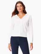 Off-white V-neck sweater with a geometric eyelet detail at the neckline.  Long sleeves.
