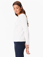 Off-white long-sleeve sweater with eyelet neckline detail.