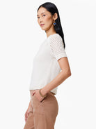 Off-white crochet-detail sweater tee with short sleeves.  The crochet is on the shoulders and upper sleeves.