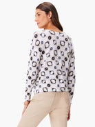 White sweater with grey, black, and beige abstract print.  Long sleeves, ribbed hem.
