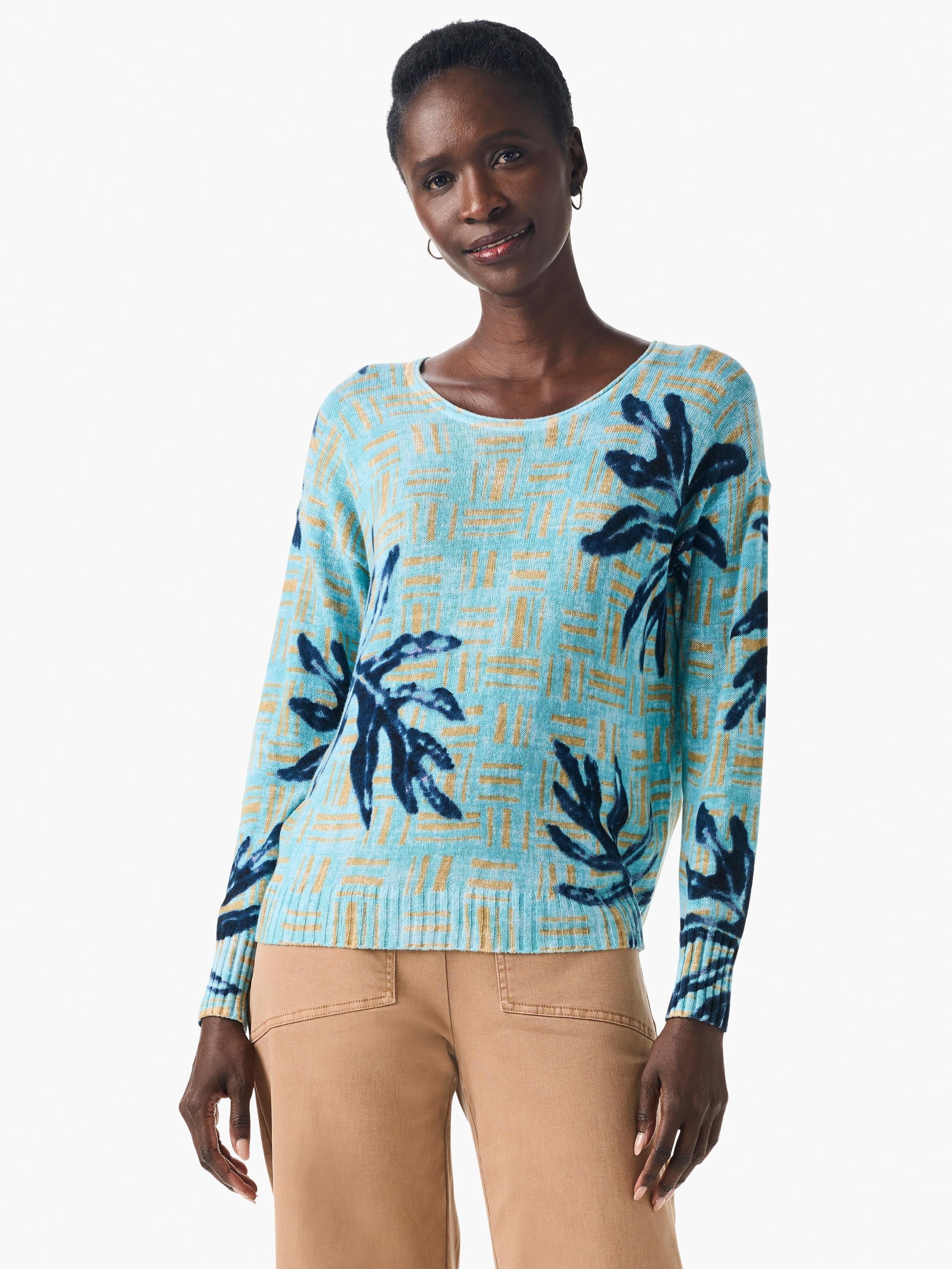 Light blue sweater with dark blue and gold leaf pattern on a textured background. Long sleeves, round neck.