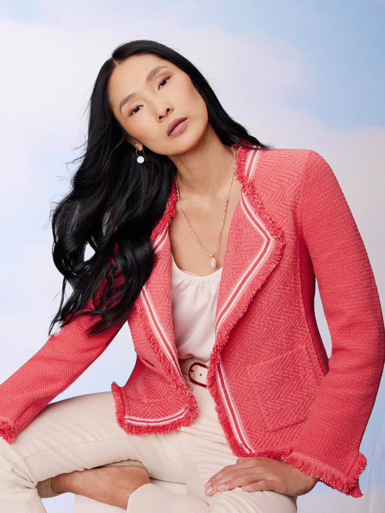 Coral knit jacket with white ribbon trim and fringe detail. Herringbone texture.