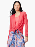 Long-sleeved coral pink knit cardigan, shown tied at the waist over a lighter pink top.
