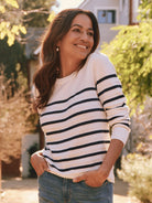 Cream cashmere sweater with navy blue horizontal stripes, long sleeves, and a round neckline.