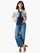 Off-white sweater with navy blue stripes. Model also wears a navy blue scarf with light gray floral pattern.
