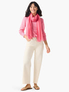 Pink cashmere sweater with button shoulders.  Model wears it with a pink scarf and off-white pants.