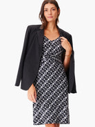 Black dress with a white and gray geometric pattern, V-neck, and a knot detail at the waist.  A black blazer is draped...