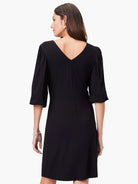 Black V-neck knit dress, elbow-length sleeves with slight puff at shoulder.  A-line silhouette.