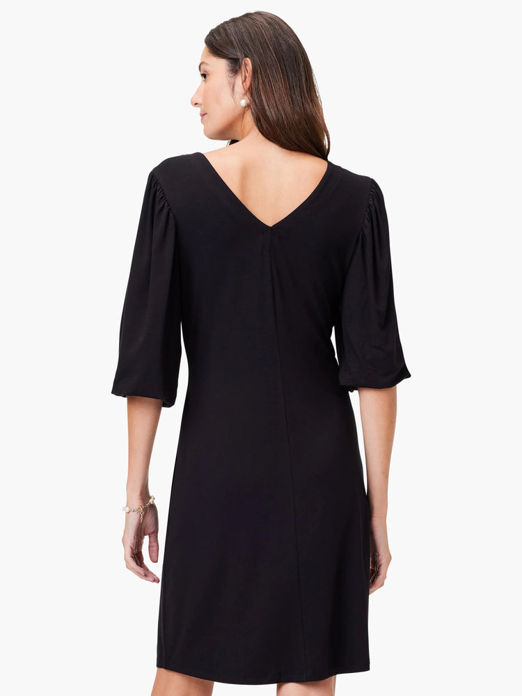 Black V-neck knit dress, elbow-length sleeves with slight puff at shoulder.  A-line silhouette.