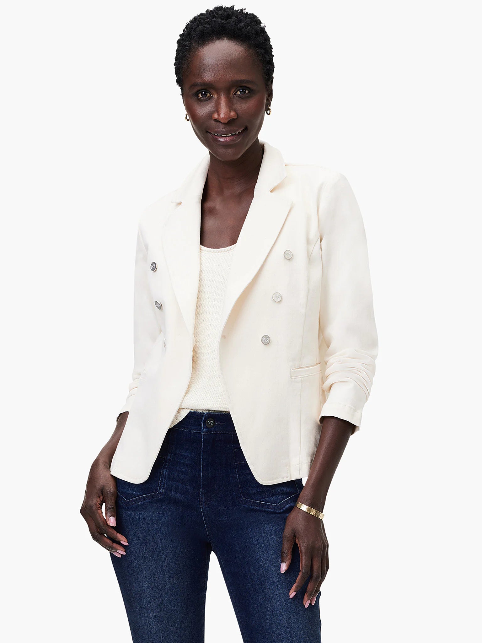 Off-white double-breasted blazer with silver buttons, shown on a model with dark-wash jeans.